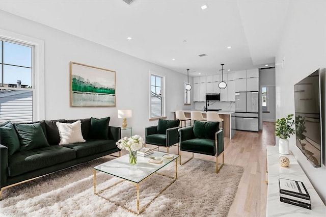living room featuring light wood finished floors, plenty of natural light, and recessed lighting