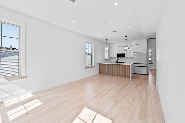 kitchen featuring freestanding refrigerator, baseboards, modern cabinets, light wood-style floors, and light countertops