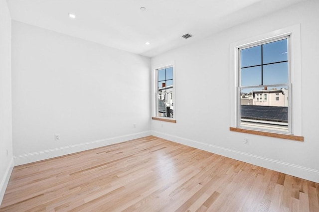 empty room with light wood finished floors, baseboards, visible vents, and recessed lighting