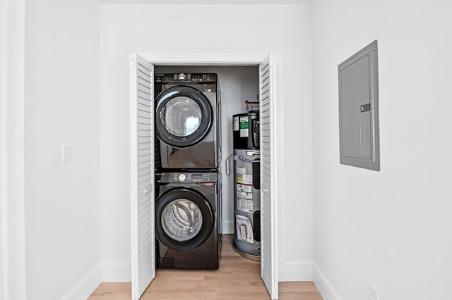 washroom featuring electric panel, wood finished floors, laundry area, water heater, and stacked washing maching and dryer