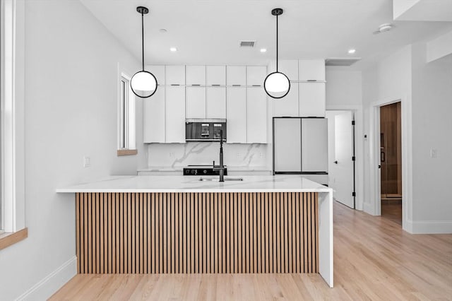 kitchen featuring stainless steel microwave, fridge, visible vents, light countertops, and white cabinets