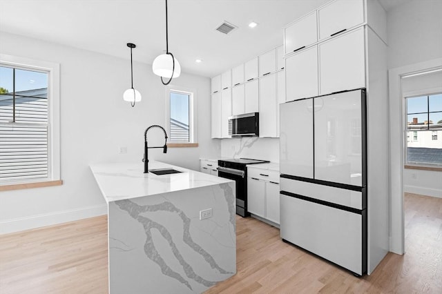 kitchen with light wood finished floors, a sink, freestanding refrigerator, visible vents, and black electric range oven