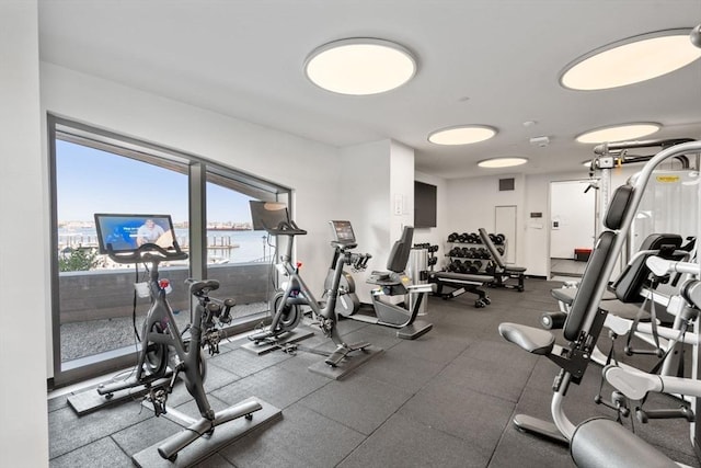 exercise room featuring a water view