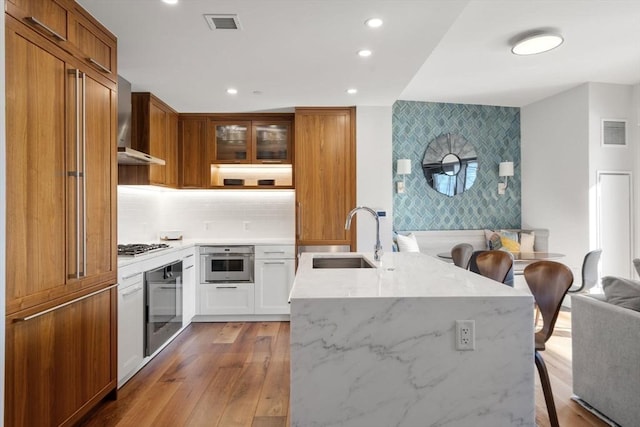 kitchen featuring appliances with stainless steel finishes, a breakfast bar, sink, white cabinets, and light stone countertops