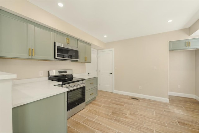 kitchen featuring stainless steel appliances, green cabinets, light countertops, baseboards, and wood tiled floor