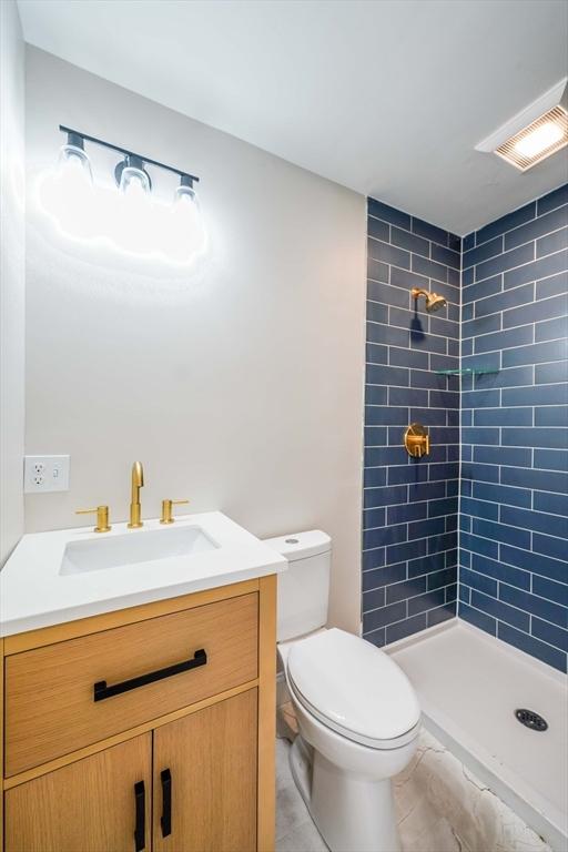 full bathroom featuring vanity, toilet, visible vents, and tiled shower