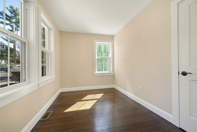 spare room featuring dark wood-style floors, visible vents, and baseboards