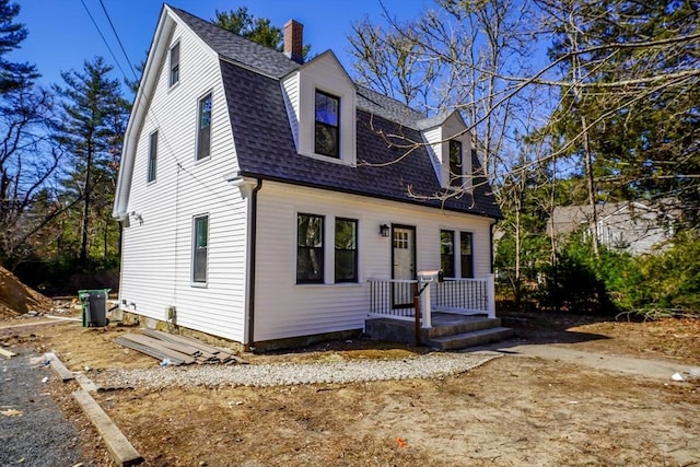 colonial inspired home with a gambrel roof and roof with shingles