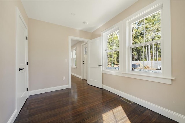 empty room featuring baseboards and dark wood-style flooring