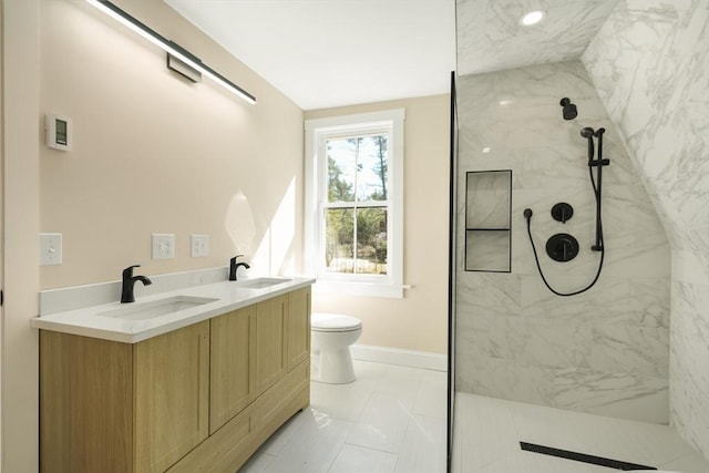 bathroom with a marble finish shower, marble finish floor, baseboards, and a sink