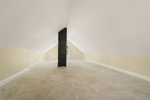 additional living space featuring baseboards, lofted ceiling, and carpet flooring