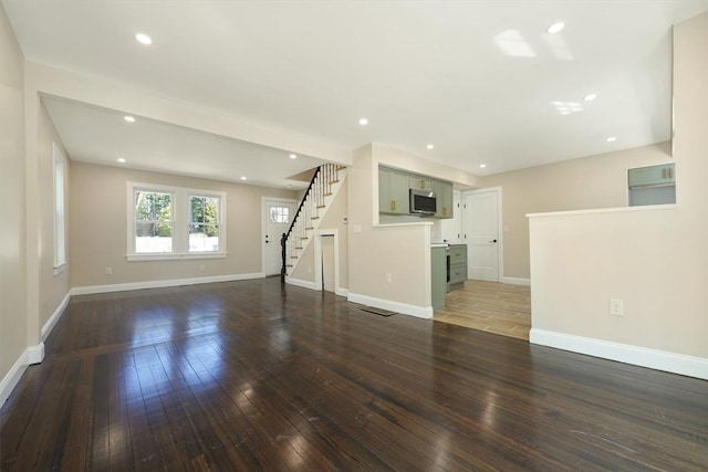 unfurnished living room with stairs, recessed lighting, baseboards, and dark wood-style flooring