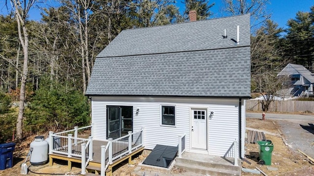 back of house featuring a wooden deck, a chimney, and a shingled roof