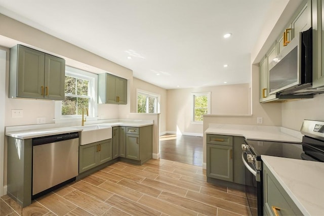 kitchen featuring a sink, stainless steel appliances, green cabinets, and wood tiled floor