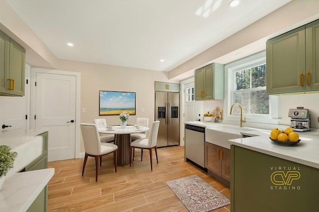 kitchen featuring wood finish floors, appliances with stainless steel finishes, and green cabinetry