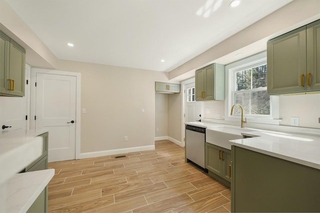 kitchen featuring baseboards, wood tiled floor, green cabinetry, dishwasher, and a sink