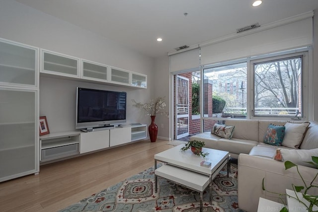 living room with light wood finished floors, recessed lighting, and baseboards