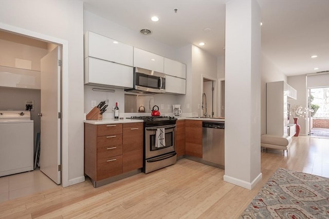 kitchen with washer / clothes dryer, stainless steel appliances, modern cabinets, brown cabinets, and white cabinets