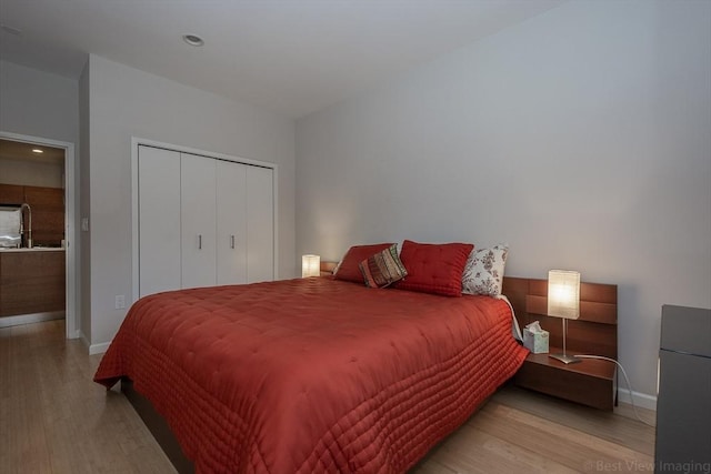 bedroom with wood finished floors, baseboards, a closet, and recessed lighting