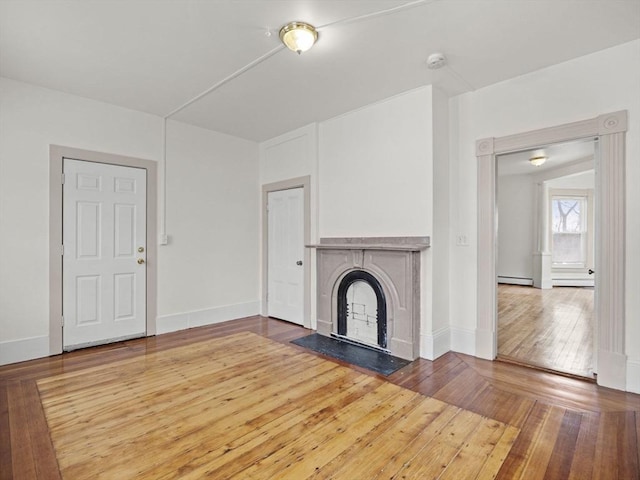 unfurnished living room featuring baseboard heating and hardwood / wood-style flooring