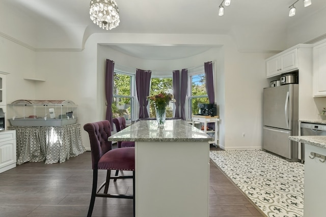 kitchen with white cabinetry, light stone counters, appliances with stainless steel finishes, and a kitchen island