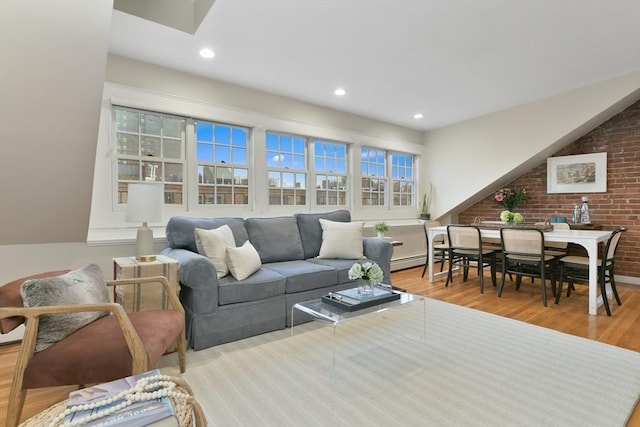 living room with a baseboard radiator, light hardwood / wood-style flooring, and brick wall