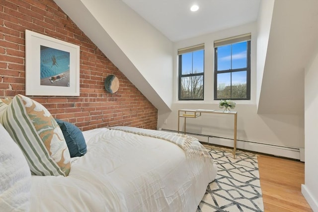 bedroom featuring a baseboard radiator, brick wall, and light hardwood / wood-style flooring