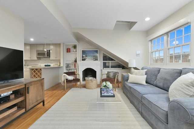 living room featuring a brick fireplace and light wood-type flooring