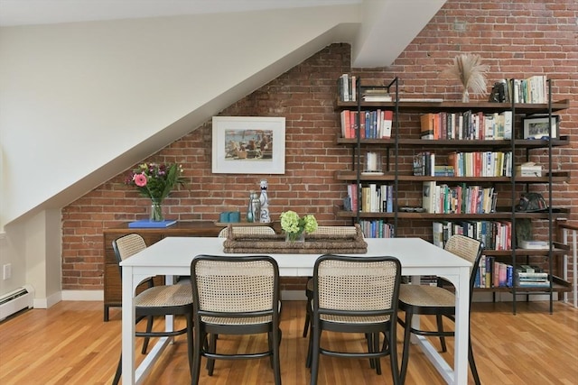 dining area with brick wall, a baseboard radiator, and wood-type flooring