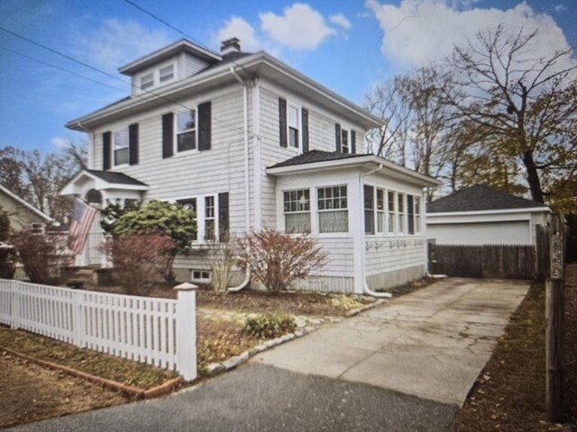 traditional style home with a chimney, a detached garage, and fence