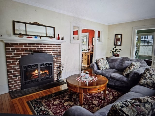 living room featuring ornamental molding, a brick fireplace, and hardwood / wood-style floors