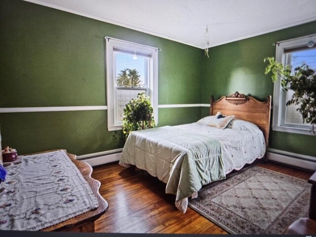 bedroom featuring baseboards, a baseboard heating unit, baseboard heating, and wood finished floors