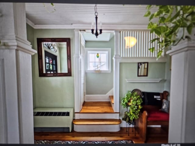 interior space with crown molding, radiator, wood-type flooring, and a chandelier