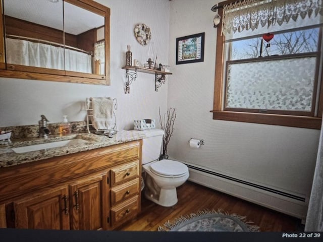 full bathroom featuring toilet, wood finished floors, curtained shower, vanity, and a baseboard heating unit