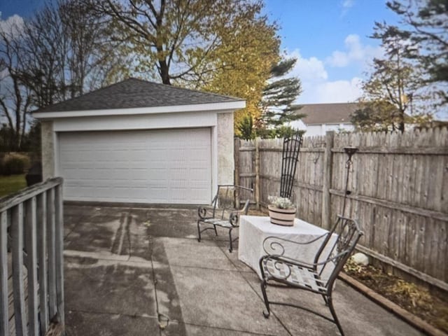 view of patio featuring a garage, an outdoor structure, and fence