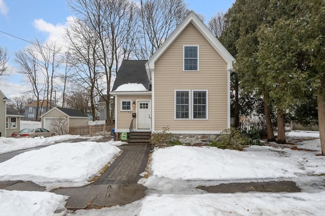 view of front of home featuring a shingled roof, a detached garage, and fence