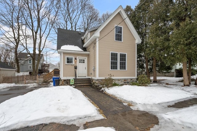 view of front facade featuring a shingled roof and fence