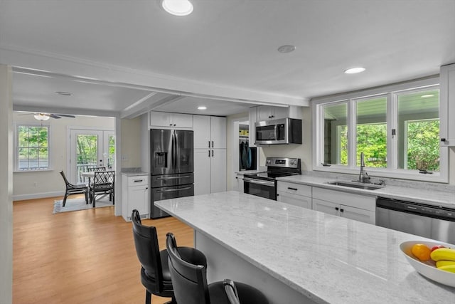 31 Brookside Dr, North Smithfield, RI 02896 - kitchen with appliances with stainless steel finishes, a sink, a kitchen breakfast bar, light wood-type flooring, and light stone counters