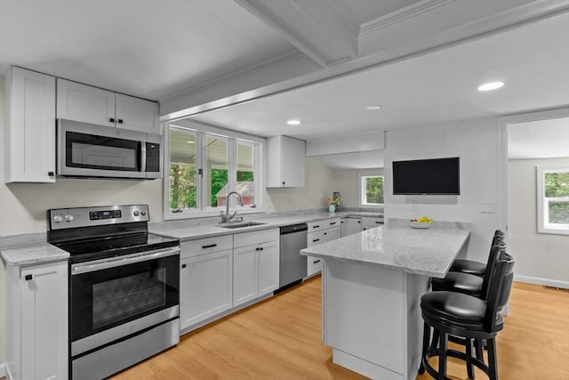 31 Brookside Dr, North Smithfield, RI 02896 - kitchen with stainless steel appliances, a sink, a peninsula, a breakfast bar, and white cabinetry