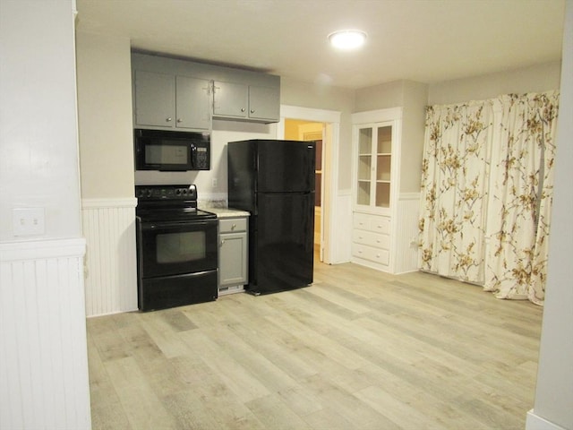 kitchen featuring gray cabinets, light hardwood / wood-style flooring, and black appliances