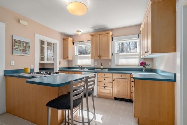 kitchen with dishwashing machine, a peninsula, a breakfast bar area, and light brown cabinetry