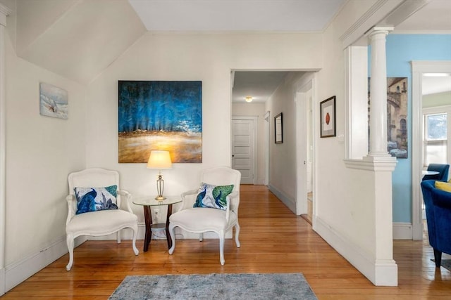 living area featuring hardwood / wood-style flooring, baseboards, and decorative columns