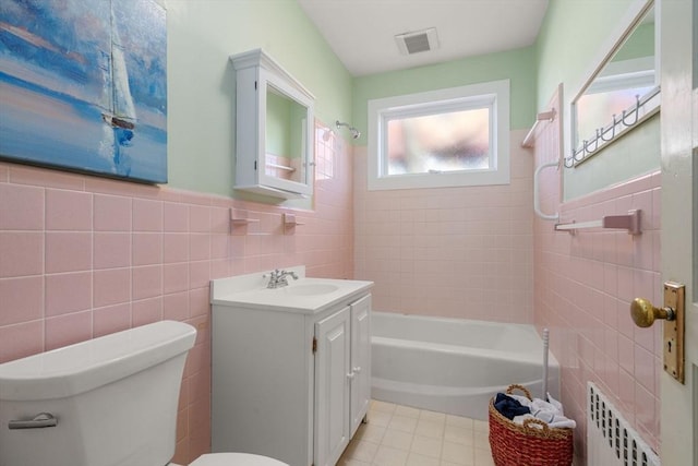 full bath with visible vents, toilet, vanity, radiator heating unit, and tile walls