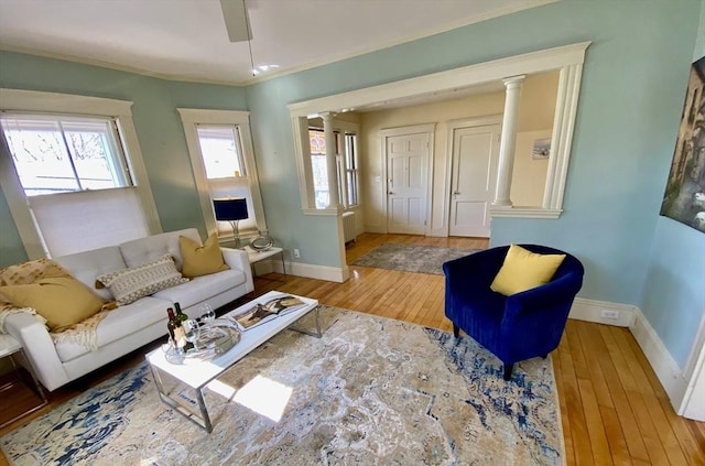 living room with a ceiling fan, baseboards, ornate columns, ornamental molding, and hardwood / wood-style flooring