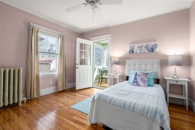 bedroom with ornamental molding, wood-type flooring, radiator, baseboards, and ceiling fan