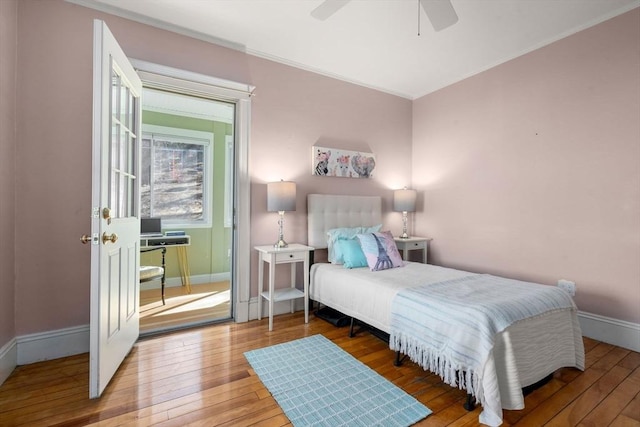 bedroom with a ceiling fan, crown molding, baseboards, and wood-type flooring