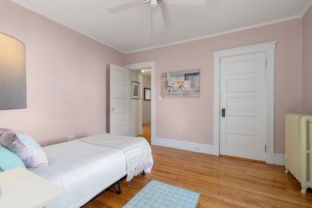 bedroom with radiator, ceiling fan, baseboards, ornamental molding, and wood finished floors