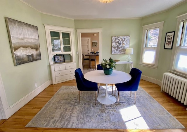 dining room featuring radiator, crown molding, baseboards, and wood finished floors