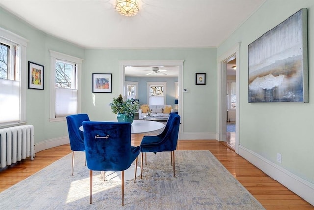 dining space with radiator, wood finished floors, and baseboards