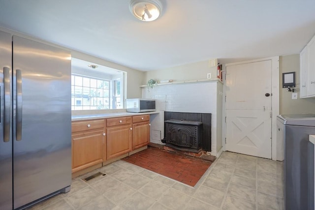 137 High St, Danvers, MA 01923 - kitchen featuring stainless steel refrigerator, a wood stove, washer / clothes dryer, and light countertops